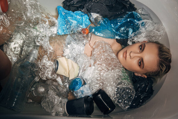 top view of beautiful woman among plastic rubbish in bathtub, eco concept