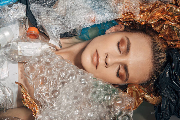 top view of of woman with closed eyes among waste in bathtub, eco concept