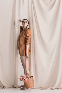 perde arka planda duran çanta çiçek taşıyan şık modelyan görünümü