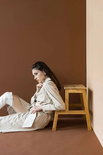 Πλευρική Όψη Του Κομψό Μοντέλο Μπεζ Καμπαρντίνα Κάθεται Στο Πάτωμα — Φωτογραφία Αρχείου