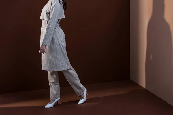 茶色の背景に歩いてトレンディな服のモデルの側面図とコピースペース — ストック写真