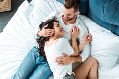 yatakta erkek arkadaşı yatarken gülümseyen kız arkadaşı üst görünümü