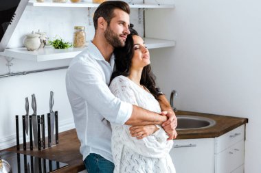 man gently embracing happy woman at home clipart
