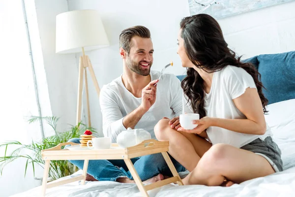 Hombre Feliz Alimentando Mujer Con Taza Cama — Foto de Stock