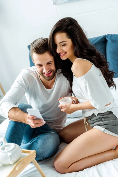Happy Woman Holding Cup Tea Bed Morning While Boyfriend Using — Stock Photo, Image