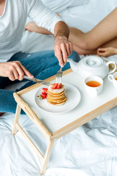 Cropped View Man Eating Pancakes Strawberries Drinking Tea Bed — Stock Photo, Image