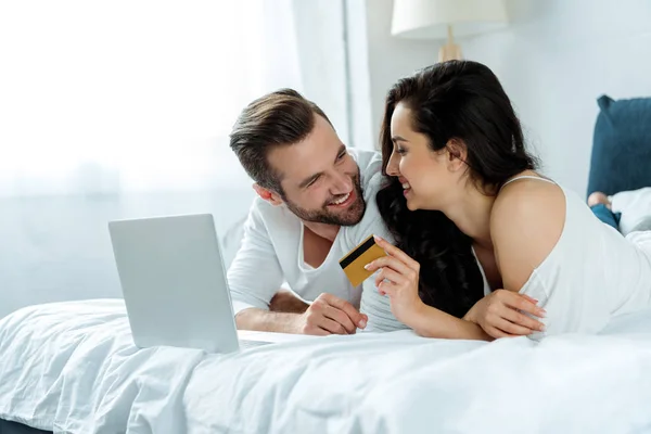 행복한 부부는 카드를 들고있는 노트북 침대에 — 스톡 사진