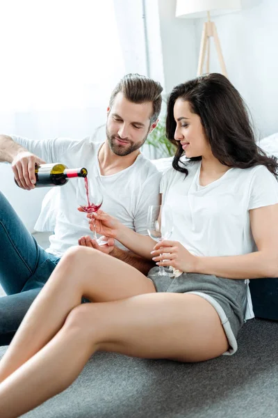 男朋友和女朋友坐在地板上 用玻璃杯把酒从瓶子里倒进红酒 — 图库照片