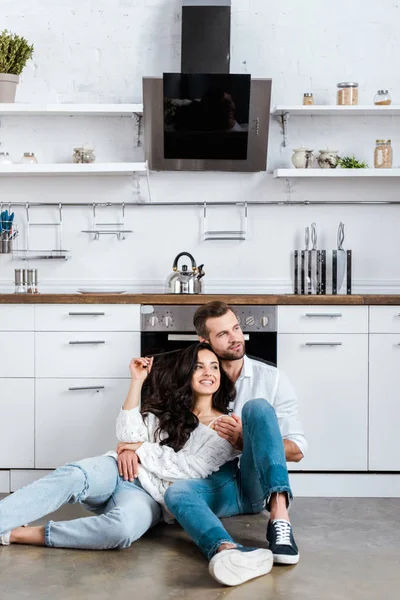 Happy Couple Sitting Floor Hugging Kitchen Looking Away — Stock Photo, Image