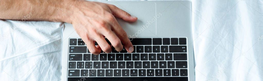 panoramic shot of man typing on laptop keyboard, illustrative editorial