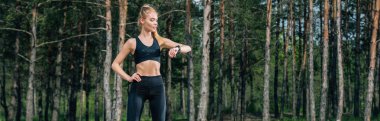 kalça eliyle duran ve fitness izci bakarak atletik kadın panoramik çekim 