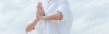 panoramic shot of young woman with praying hands near sky clipart