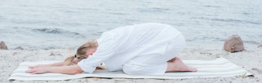 sarışın genç kadın rahatlatıcı ve deniz kenarında yoga mat yoga panoramik çekim 