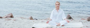 nehir yakınında yoga pratik kapalı gözleri ile huzurlu sarışın genç kadının panoramik çekim 