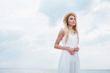 hasır şapka ve beyaz elbise çekici genç kadın düşük açılı görünümü 