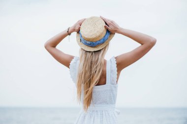 genç sarışın kadın ayakta ve hasır şapka dokunmadan geri görünümü