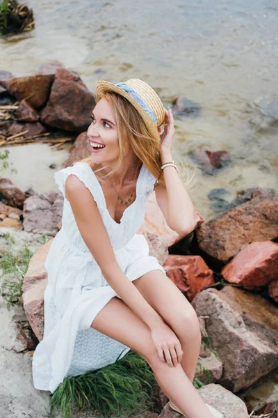 Overhead View Cheerful Blonde Girl Touching Straw Hat While Sitting — Stock Photo, Image