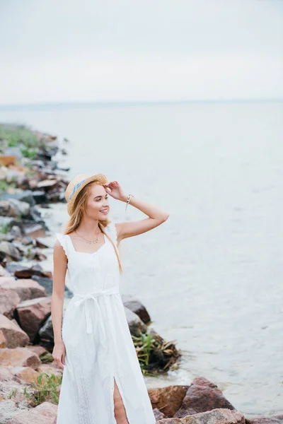 Cheerful Young Blonde Woman Touching Straw Hat Looking Sea — Stock Photo, Image