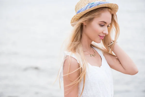 海の近くに立っているわら帽子でかわいいと陽気なブロンドの女の子 — ストック写真