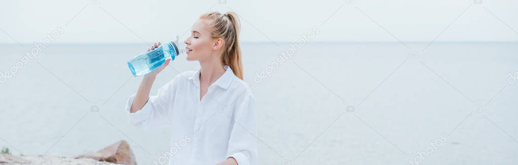 panoramic shot of happy blonde woman drinking water 