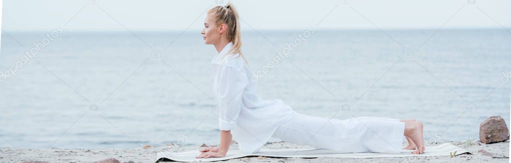 panoramic shot of young woman practicing yoga near river 