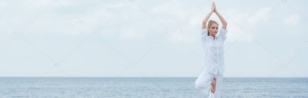 panoramic shot of blonde woman with closed eyes practicing yoga 