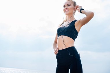 kalça el ile ayakta iken müzik dinle neşeli atletik kız düşük açı görünümü 