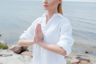 cropped view of young woman with praying hands near sea  clipart