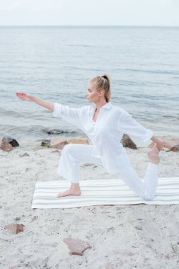 deniz kenarında yoga mat yoga çekici sarışın kadın yan görünümü 
