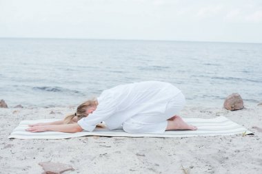 sarışın genç kadın rahatlatıcı ve deniz kenarında yoga mat yoga 