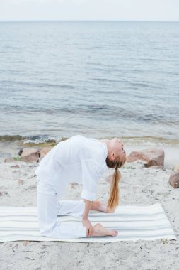 kapalı gözlü sarışın genç kadın deniz kenarında yoga mat yoga 