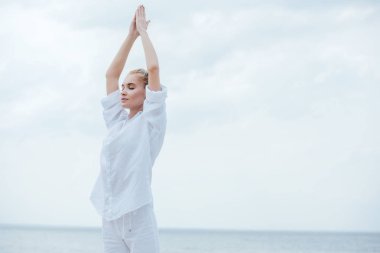 attractive girl with closed eyes practicing yoga and standing with praying hands  clipart