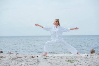 yoga yapan ve uzanmış ellerle ayakta duran çekici kız yan görünümü