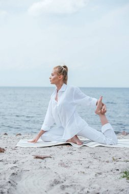 nehir yakınında yoga yapan sarışın genç kadının yan görünümü 