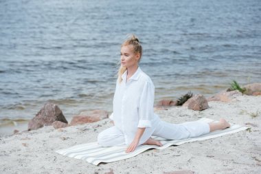 yoga mat nehir yakınında yoga yapan çekici sarışın genç kadın