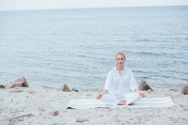 nehir yakınında yoga yapan huzurlu ve güzel sarışın genç kadın 