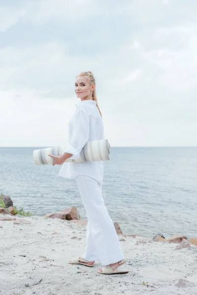 Zambind Blonda Femeie Holding Yoga Mat Picioare Lângă Mare — Fotografie, imagine de stoc