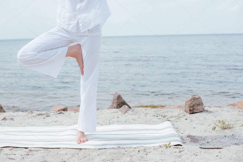 cropped view of young woman doing yoga near sea 