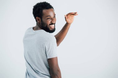gri üzerinde izole sallayarak gri t-shirt gülümseyen afrikalı amerikalı adam