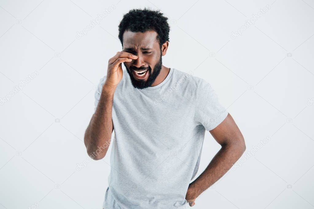 upset african american man in grey t-shirt crying isolated on grey