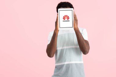 Kiev, Ukrayna - 17 Mayıs 2019: Huawei uygulaması ile dijital tablet bağırıp gösteren, pembe yekpiştirilen Afrikalı Amerikalı adam