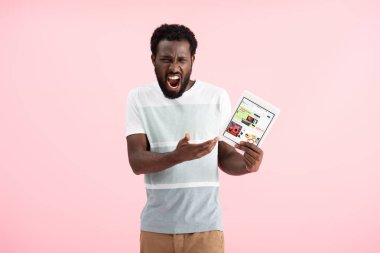 Kiev, Ukrayna - 17 Mayıs 2019: duygusal afro-amerikan adam bağırarak ve ebay uygulaması ile dijital tablet gösteren, pembe izole