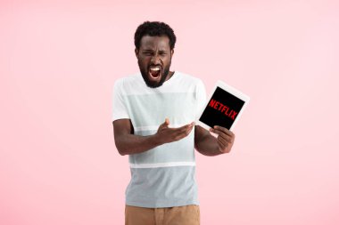 Kiev, Ukrayna - 17 Mayıs 2019: duygusal afro-amerikan adam bağırıyor ve netflix uygulaması ile dijital tablet gösteren, pembe izole