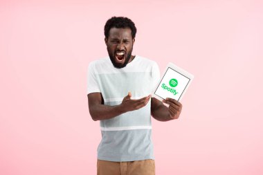 Kiev, Ukrayna - 17 Mayıs 2019: duygusal afro-amerikan adam bağırıyor ve spotify uygulaması ile dijital tablet gösteren, pembe izole