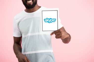 Kiev, Ukrayna - 17 Mayıs 2019: Skype uygulaması ile dijital tablet gösteren Afrikalı Amerikalı adamın kırpılmış görünümü, pembe izole