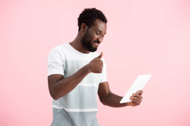 pembe izole dijital tablette görüntülü sohbet yaparken başparmak gösteren gülümseyen afrikalı amerikalı adam