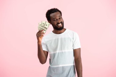 gülümseyen afrikalı amerikalı adam dolar banknotlar tutan, pembe izole