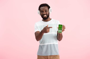 afro-amerikan adam kulaklık ile müzik dinleme ve sağlık uygulaması ile akıllı telefon işaret, pembe izole 