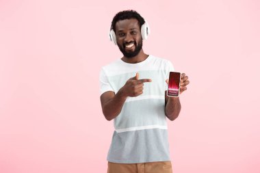 afro-amerikan adam kulaklık ile müzik dinleme ve ticaret kursları ile akıllı telefon işaret, pembe izole 
