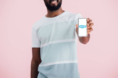 Kiev, Ukrayna - 17 Mayıs 2019: pembe izole skype uygulaması ile akıllı telefon gösteren Afrikalı Amerikalı adam kırpılmış görünümü 